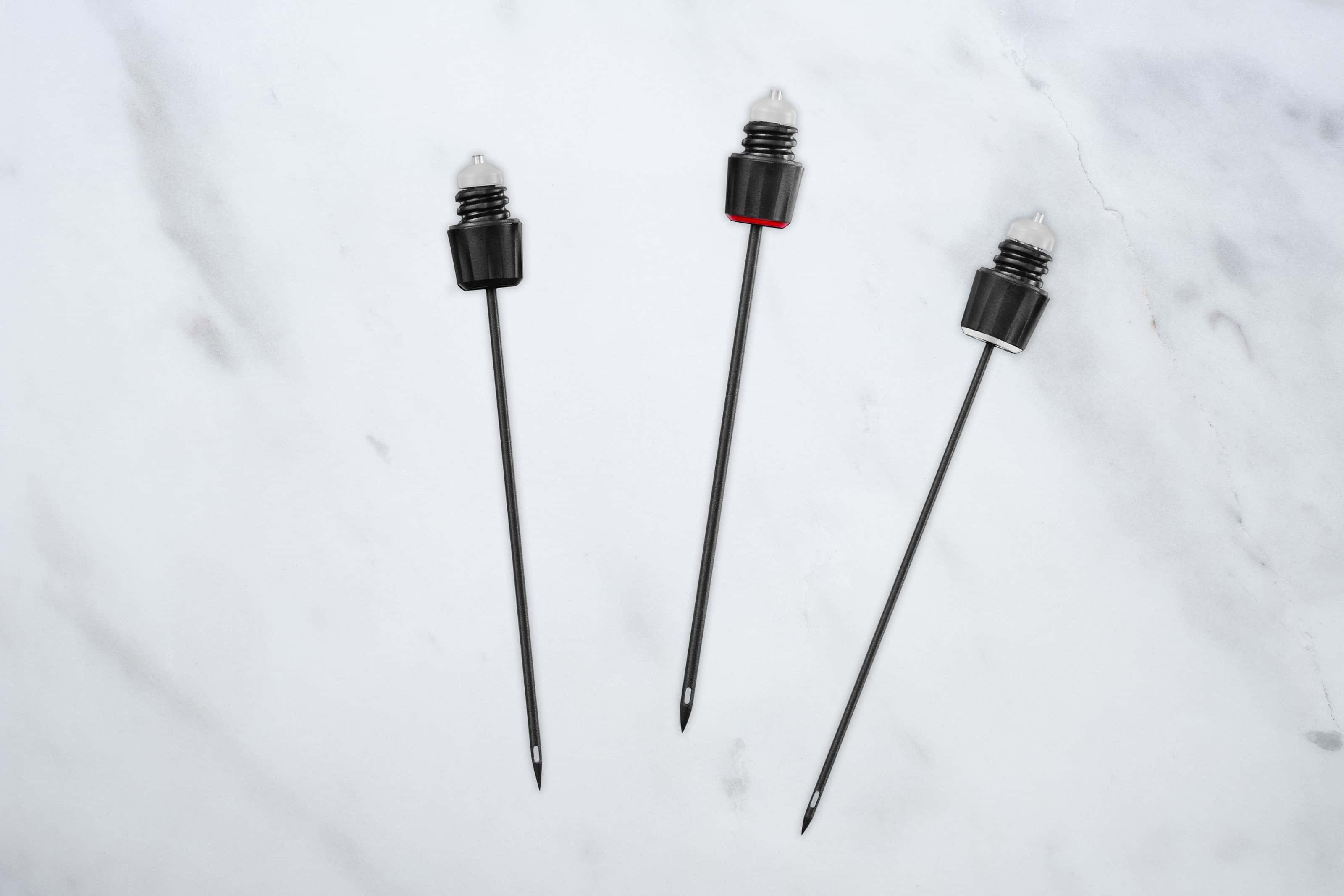 Three Coravin Timeless wine system needles — Standard, Fast Pour, and Vintage — displayed on a marble surface, showcasing their durable stainless steel design and non-stick coating.