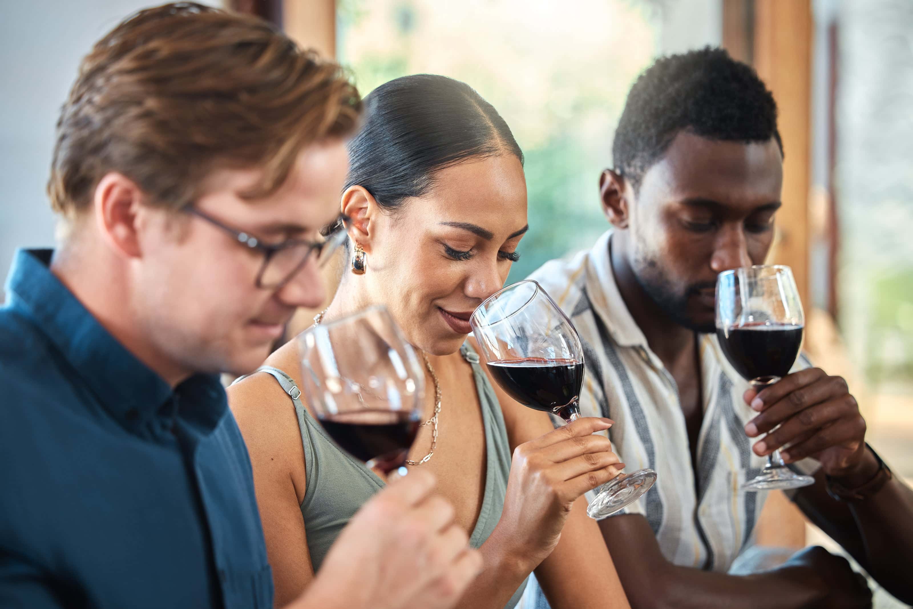 3 people smelling a glasses of wine. 