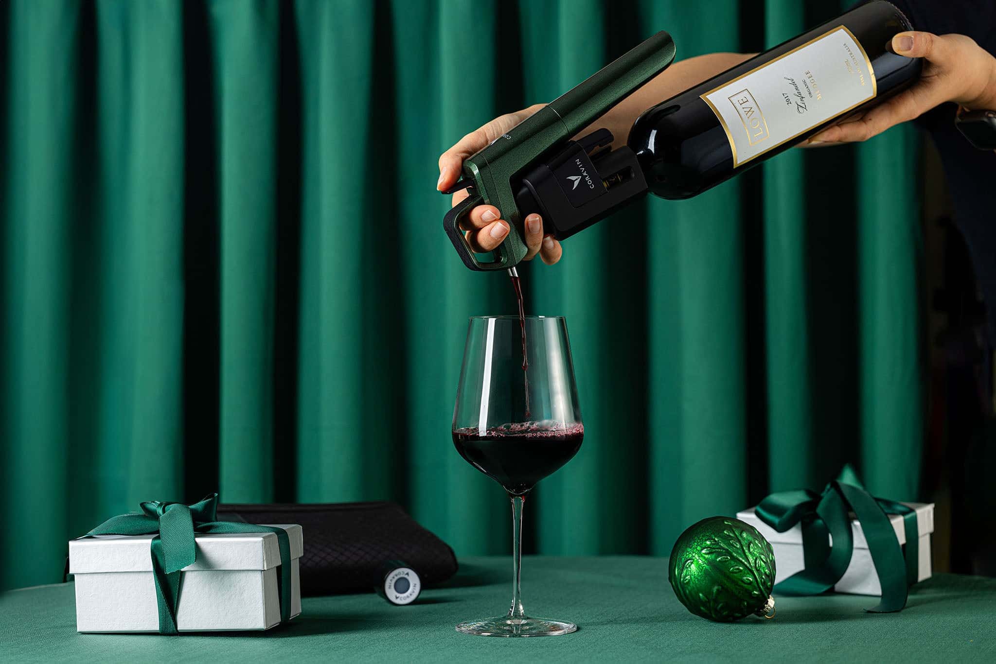 Timeless Six plus against green curtain background, with red wine and gifts wrapped in green bows