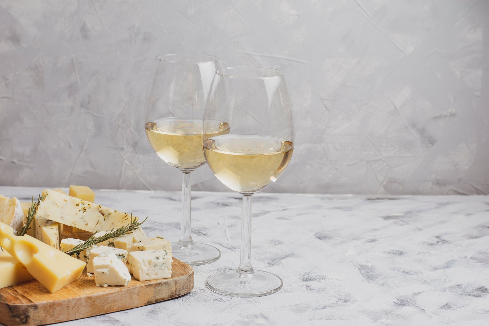 two glasses of dry white wine with cheese board