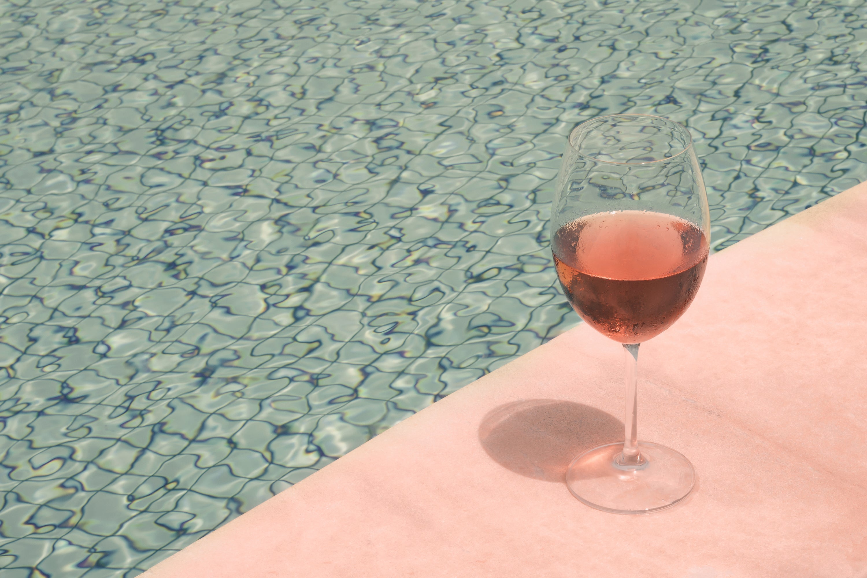 what is rose wine - glass of pink wine on pink surface next to water