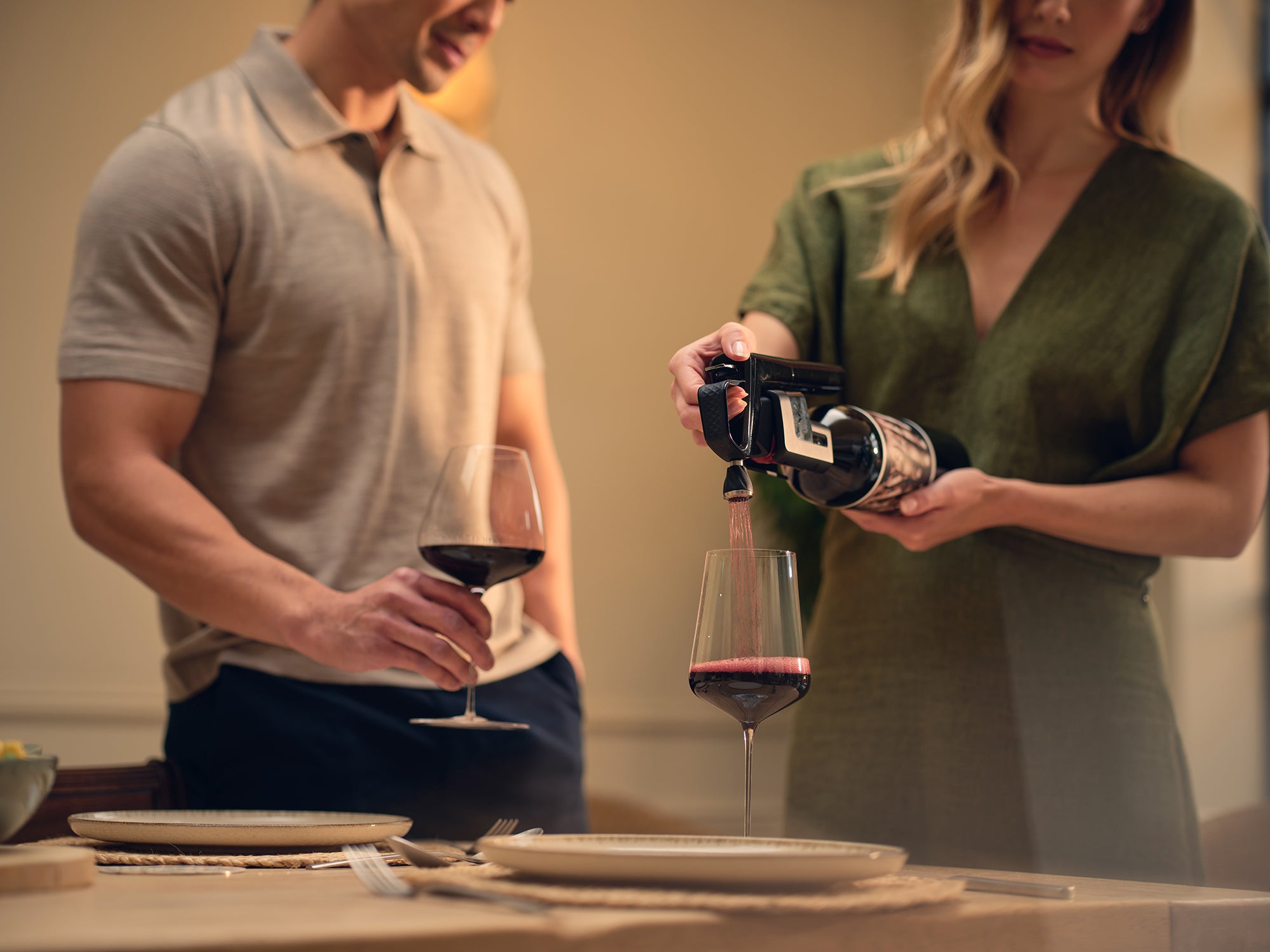 Woman pouring red wine into a glass held by a man at a dining table.